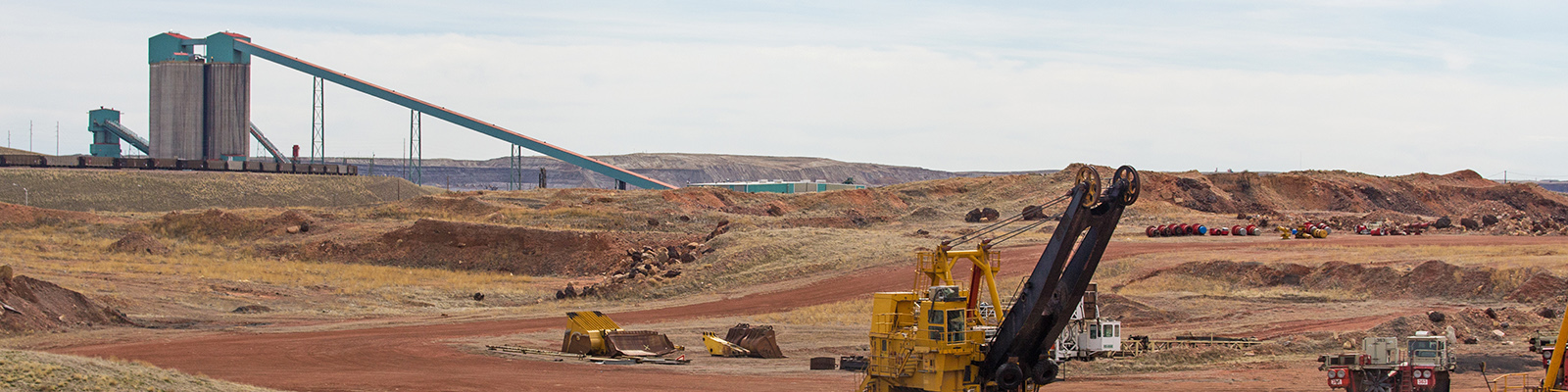 hero-image Industrial coal mining equipment and silos beside a row of railway cars in a Wyoming valley landscape.