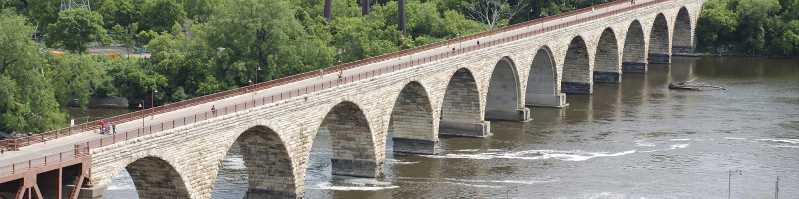 The Stone Arch Bridge is a former railroad bridge crossing the Mississippi River at Saint Anthony Falls in downtown Minneapolis, Minnesota, shown here on a sunny day.