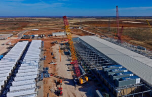 Aerial construction view shows data center structures BESS batteries red cranes and metal framing.