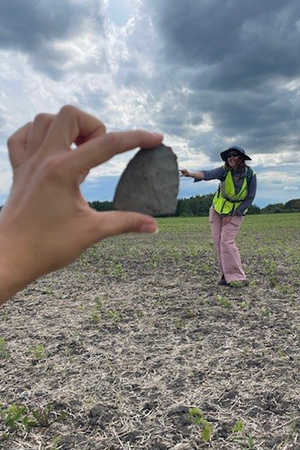 Jessie examines an artifact identified during fieldwork, helping document and evaluate potential cultural resources within the project area.