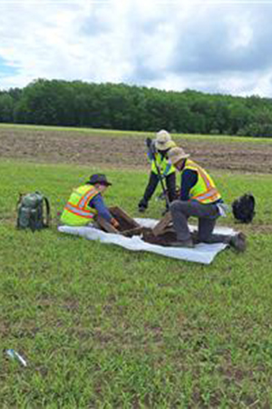 Cultural resources interns Isaiah Gardell and Jessie Johnson spend time with a Barr colleague on site in a sunny field, sharing ideas and experiences while gaining experience in cultural resources work.