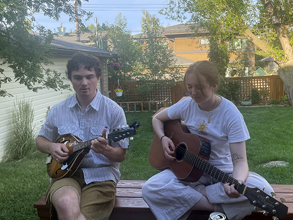 Shaye plays guitar with family in the outdoors.