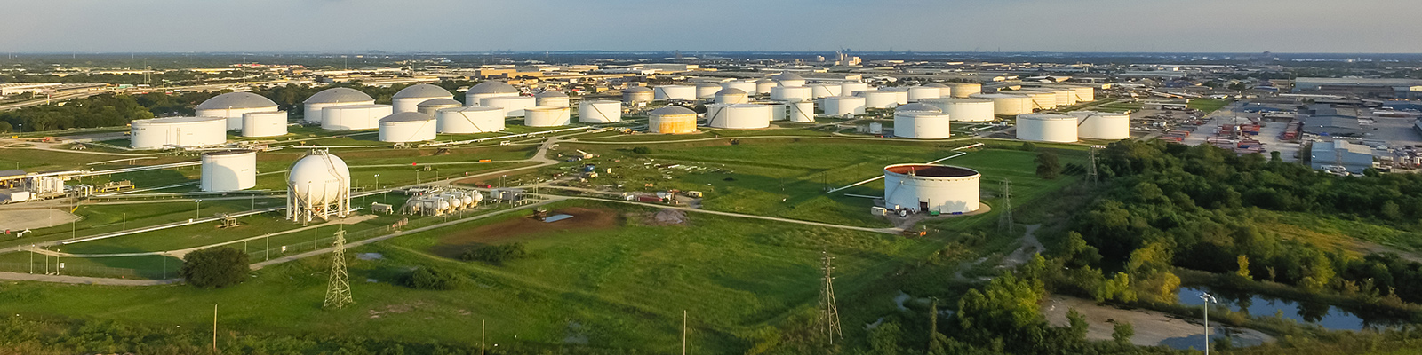 Aerial view of a large tank farm with dozens of white storage tanks spread across an industrial site.