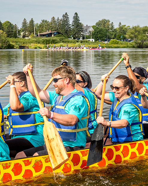 Barr employees row a dragon boat through the water on a beautiful sunny day during the Lake Superior Dragon Boat Festival.
