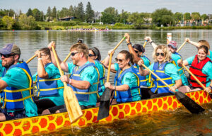 Barr employees row a dragon boat through the water on a beautiful sunny day during the Lake Superior Dragon Boat Festival.