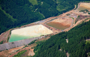 Aerial view of lined water containment ponds surrounded by forested mining operations.