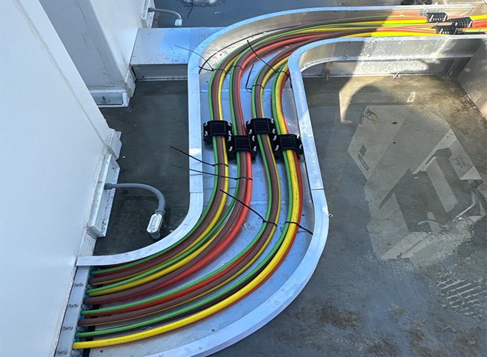 Curved cable trays carrying red, yellow, and green-coated cables