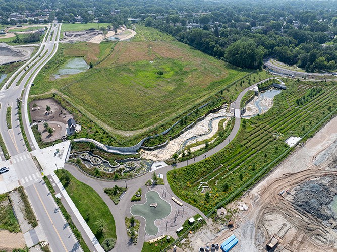 Aerial image of an engineered bedrock channel extending along public gardens and a playground on a sunny day.