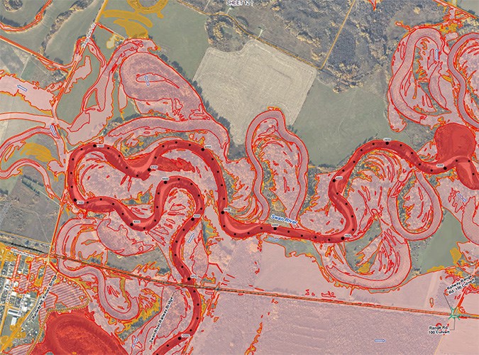 A map showing an aerial view of a meandering river with a graphic overlay depicting flood hazards in shades of red.